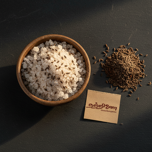 Nattrinai OMA Uppu ajwain salt in a ceramic bowl with whole carom seeds on dark slate surface with brand tag placed flat beside it